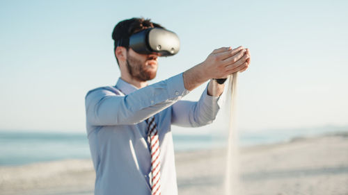 Business man practicing relaxation with virtual reality headset at the beach