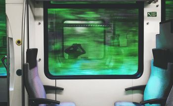 Reflection of man photographing on train window