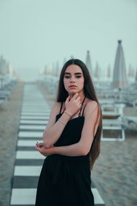 Portrait of beautiful young woman standing against sky