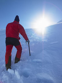 Rear view of man on snowcapped mountain against sky