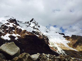 Low angle view of snowcapped mountains against cloudy sky