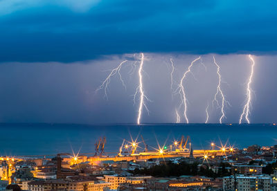 Lightning over sea against city at night