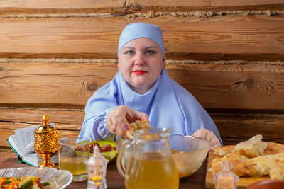 Portrait of young woman holding food on table