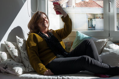 Woman sitting on bed at home