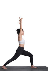 Full length of woman doing yoga on white background