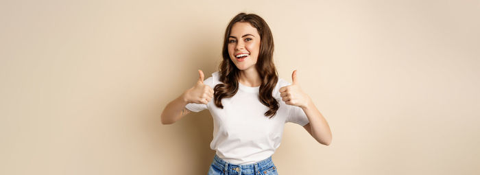 Portrait of young woman standing against wall