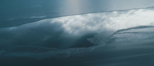 Half frozen lake with clouds reflected in water during sunset. 