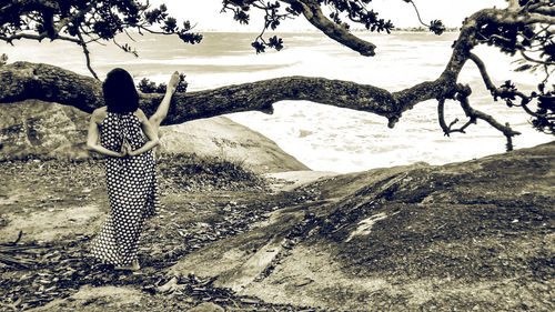 Rear view of woman standing by tree against sky