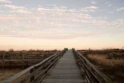 View of wooden footbridge on field against sky