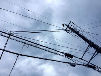 Low angle view of power lines against cloudy sky