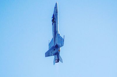 Low angle view of airplane flying against clear blue sky