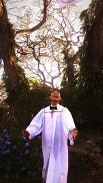 Cheerful young man in graduation gown on field