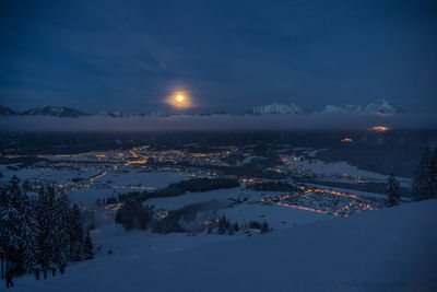 Aerial view of illuminated snow covered landscape against sky at night