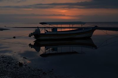 Boat moored on beach against sky during sunset