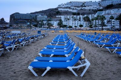 Deck chairs on beach against blue sky