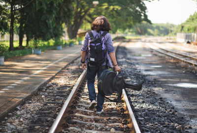 Rear view of people walking on railroad track