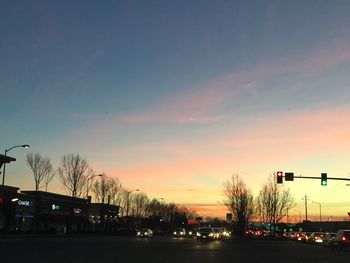 Cars on illuminated city against sky during sunset