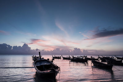 Boat moored in sea against sky during sunset
