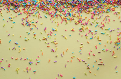 Close-up of multi colored sprinkles on yellow background