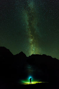 Silhouette person standing on mountain against sky at night