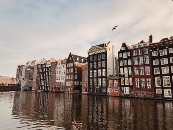 View of buildings by river against sky