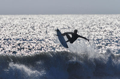 Man surfing in sea against sky