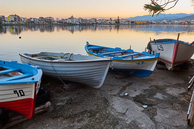 Boats moored on beach against sky during sunset