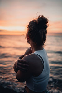 Woman looking at sea against sky during sunset