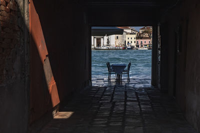 Empty chairs and table in sea against buildings