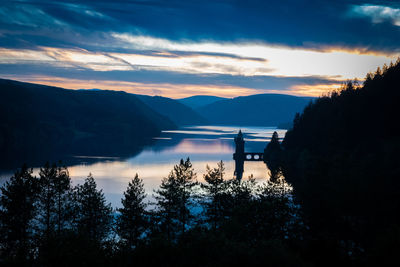 Scenic view of lake and mountains against sky at sunset