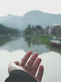 Cropped image of man hand against lake 