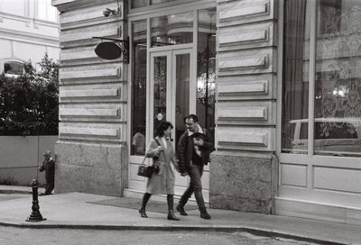 People walking on footpath by building