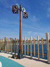 Low angle view of wooden post at beach against sky