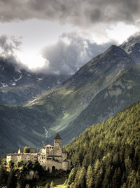 Houses on mountain against cloudy sky