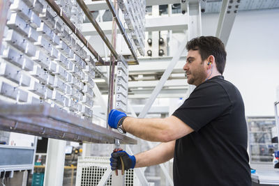 Man working in factory shop floor hanging products on rack