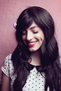 Close-up of beautiful model smiling against peach backdrop