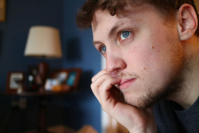 Close-up of thoughtful young man looking away at home