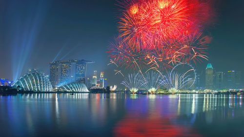 Firework display over river against sky at night