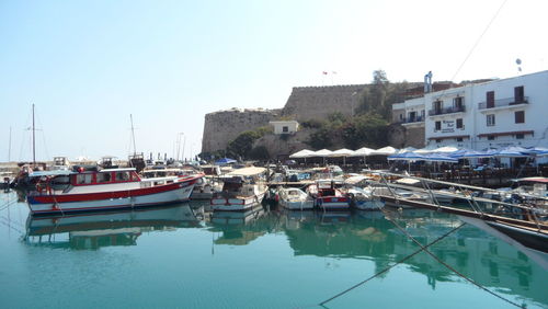 Boats moored on river against clear blue sky