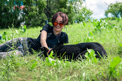 Side view of woman sitting on grassy field