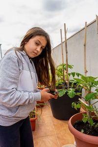 Beautiful young woman standing by potted plants