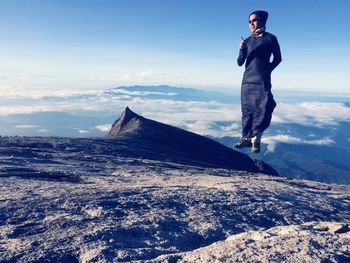 Woman levitating over mountain against sky