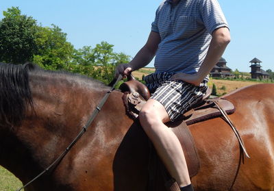 Midsection of man riding horse against sky