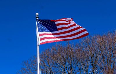 Low angle view of flag against blue sky