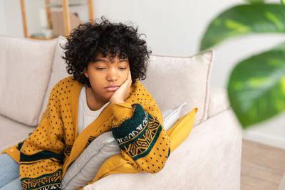 Portrait of young woman sitting on sofa at home