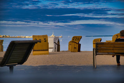 Hooded chairs on beach against sky