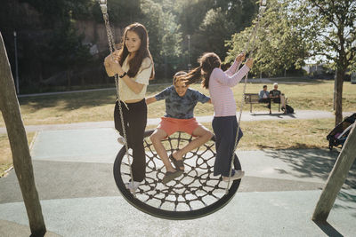 Siblings having fun swinging on swing on playground