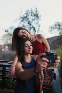 Young woman photographing while using smart phone