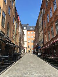 Empty road amidst buildings against sky