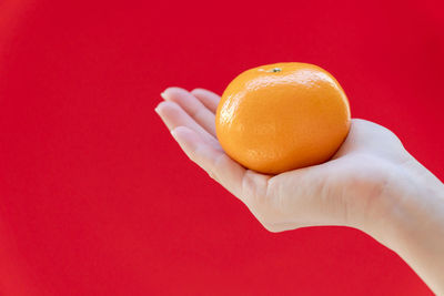 Close-up of hand holding apple against red background